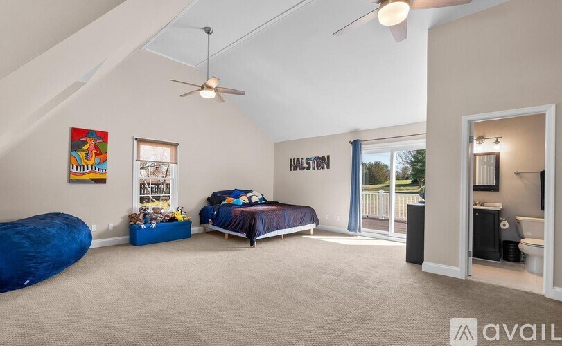 A bedroom with a bed, a blue bean bag chair, and a ceiling fan.