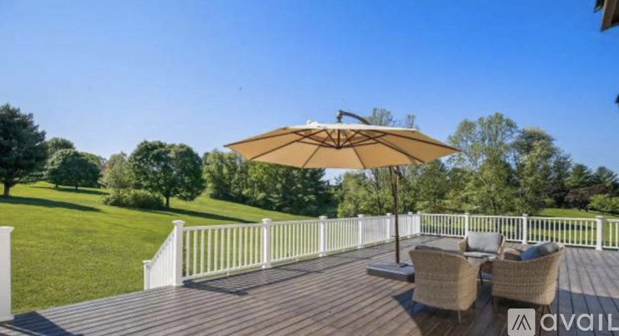 A patio with a white railing, a brown umbrella, and two chairs.