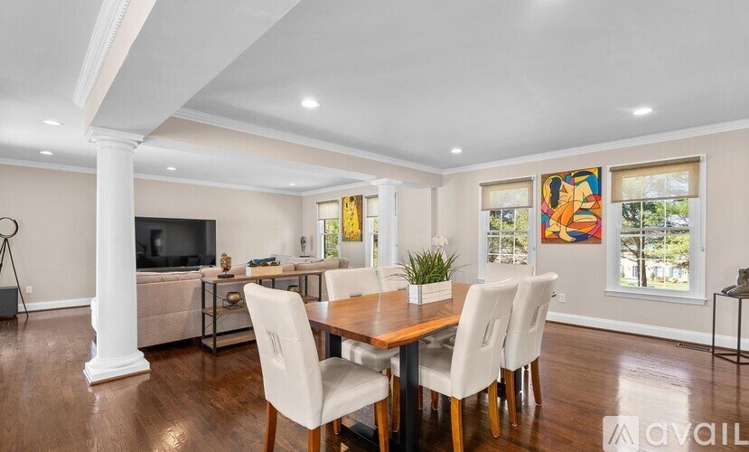 A dining room with a wooden table and white chairs.