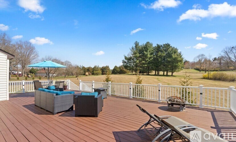 A wooden deck with a white railing and a blue umbrella.