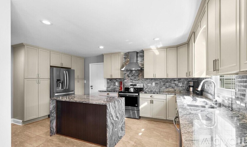 A modern kitchen with a marble countertop and stainless steel appliances.