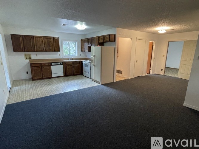 A kitchen area with a refrigerator, sink, and cabinets.