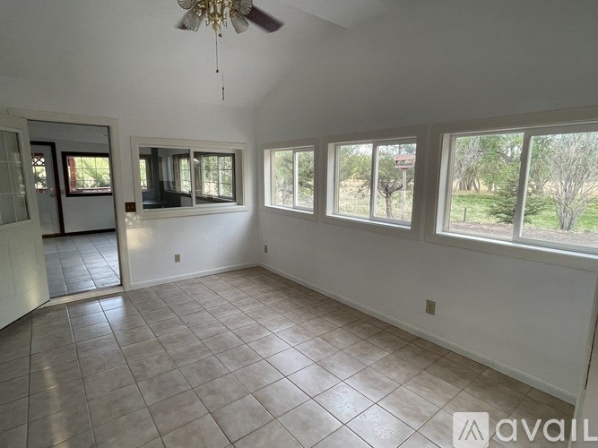 A room with a fan and large windows.