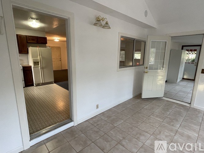 A room with a tiled floor and a glass door leading to a kitchen.
