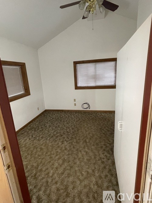 A room with a ceiling fan and carpeted floor.