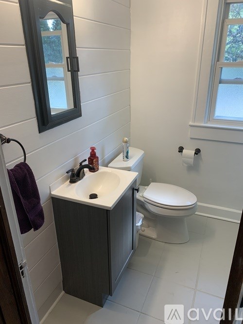 A bathroom with a toilet, sink, and mirror.