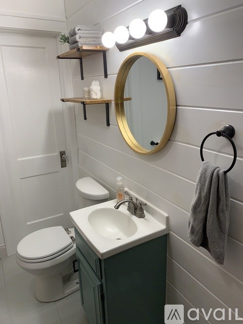 A bathroom with a white toilet, a sink, a mirror, and lights on the wall.