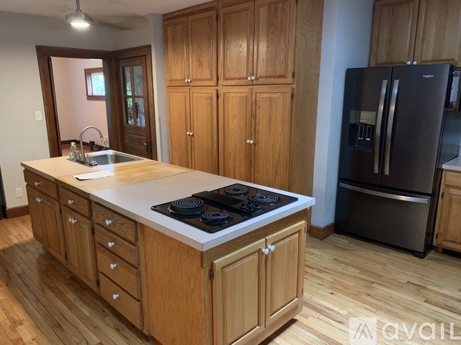 A kitchen with wooden cabinets and a black fridge.