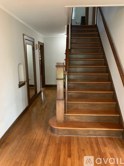 A wooden staircase with a white wall on the side.