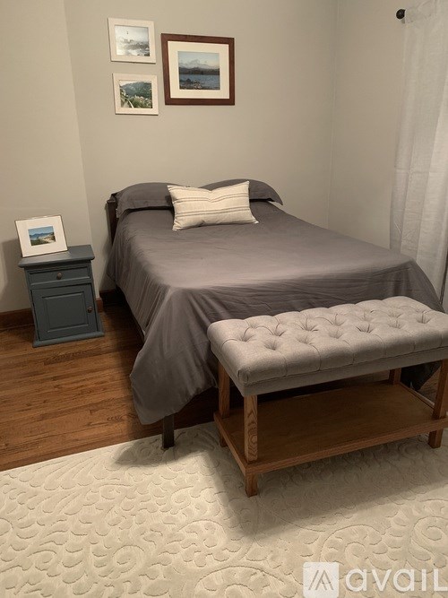 A bed with a grey sheet and a white pillow is in the image.