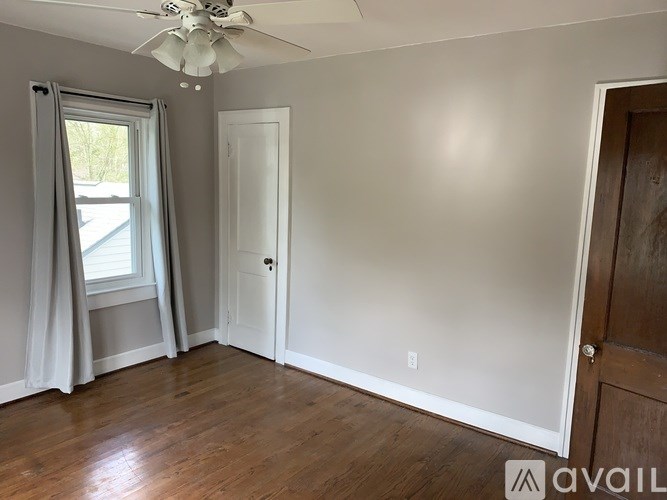 A room with a ceiling fan and a window with curtains.