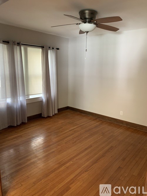 A room with a ceiling fan and wooden flooring.