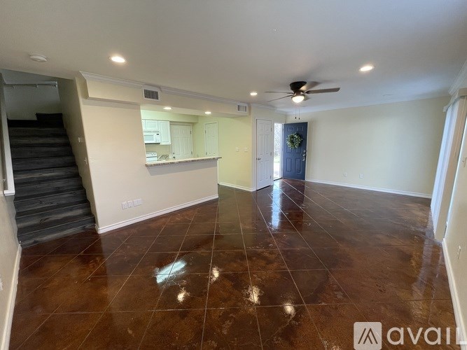 A room with brown tiled flooring and a ceiling fan.