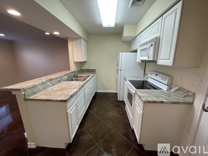 A kitchen with white cabinets and a granite countertop.