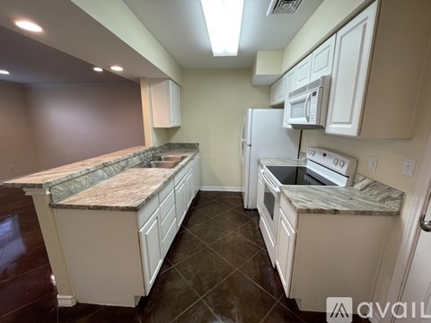 A kitchen with white cabinets and a granite countertop.
