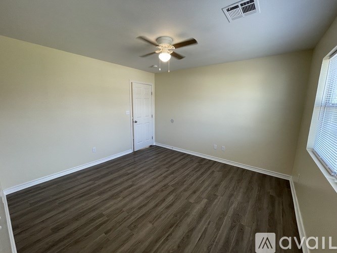 A room with a ceiling fan and wooden flooring.