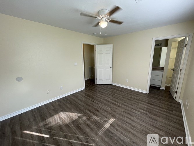 A room with a ceiling fan and wooden flooring.