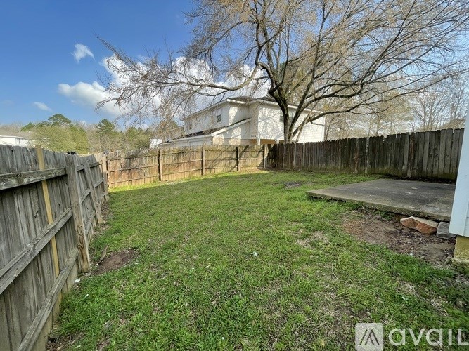 A backyard with a wooden fence and a tree.