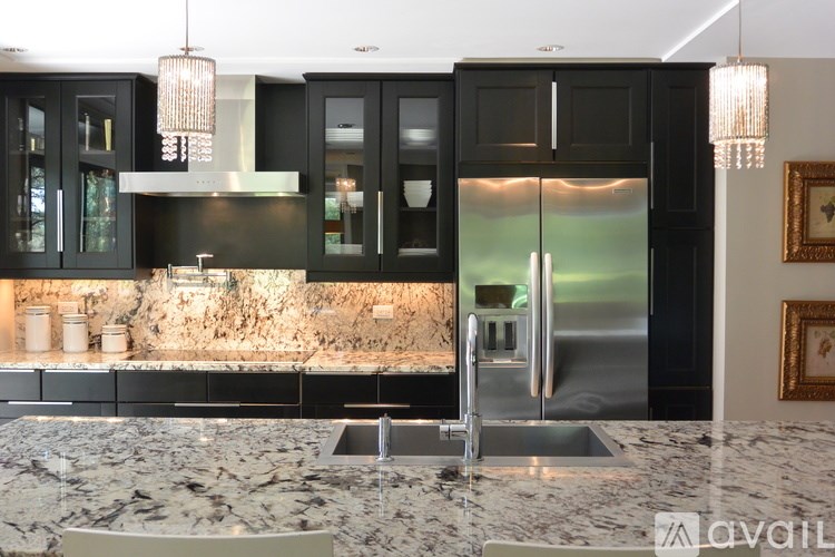 A modern kitchen with a marble countertop and a stainless steel refrigerator.