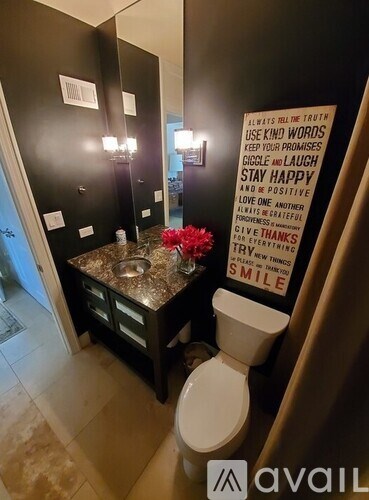 A bathroom with a toilet, sink, and a poster with positive messages.