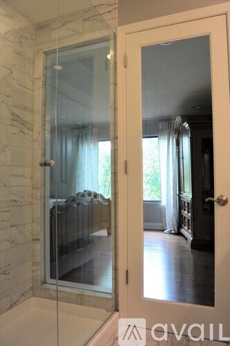 A glass door with a white frame leads to a room with a couch and a window.