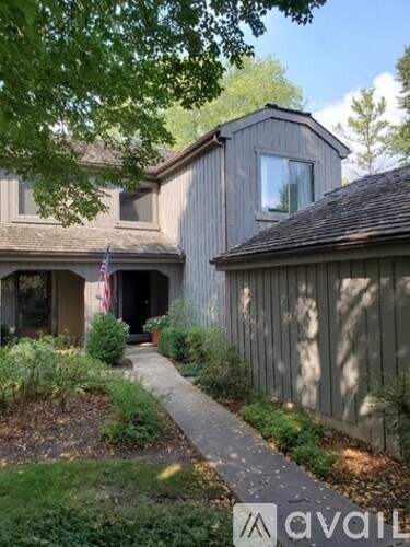 A wooden house with a flag on the porch.