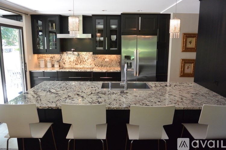 A kitchen with granite countertops and black cabinets.
