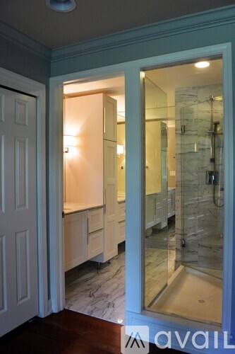 A bathroom with a glass shower door and a white door.