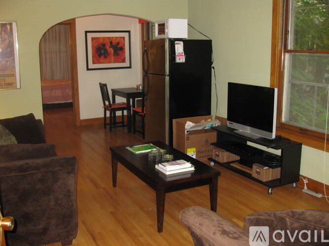 A living room with a brown couch, a black coffee table, a black refrigerator, and a black entertainment center.