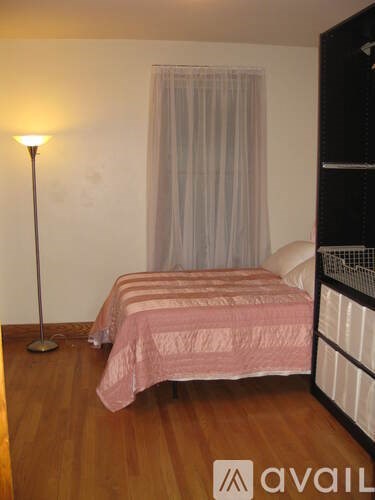 A bedroom with a pink bedspread and a floor lamp.