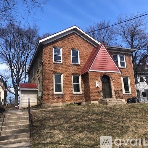 A red brick house with a triangular roof and a black door.
