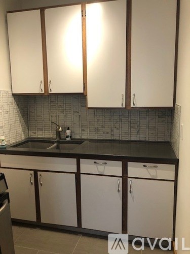 A kitchen with white cabinets and a black countertop.