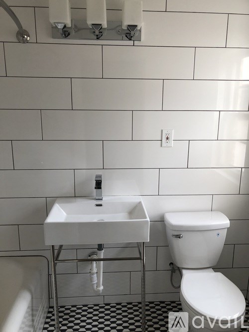 A white toilet and sink in a bathroom with white tiles.