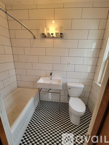A white toilet sits in a bathroom with black and white tiles.