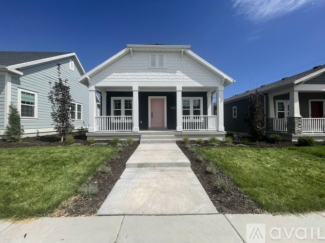 A white house with a grey roof and a red door is in front of a blue sky.
