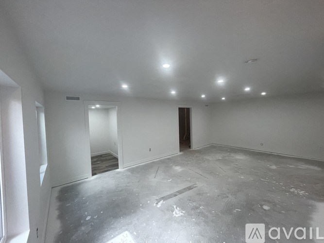 A spacious empty room with a concrete floor and white walls.