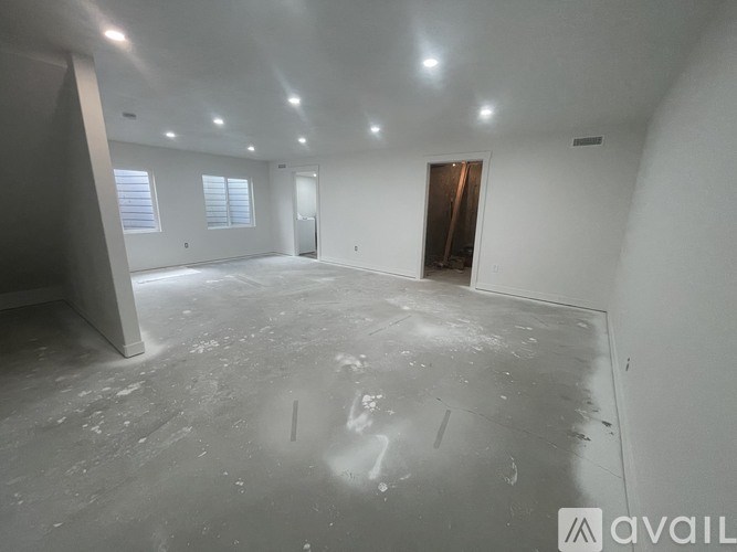 A large empty room with a concrete floor and white walls.