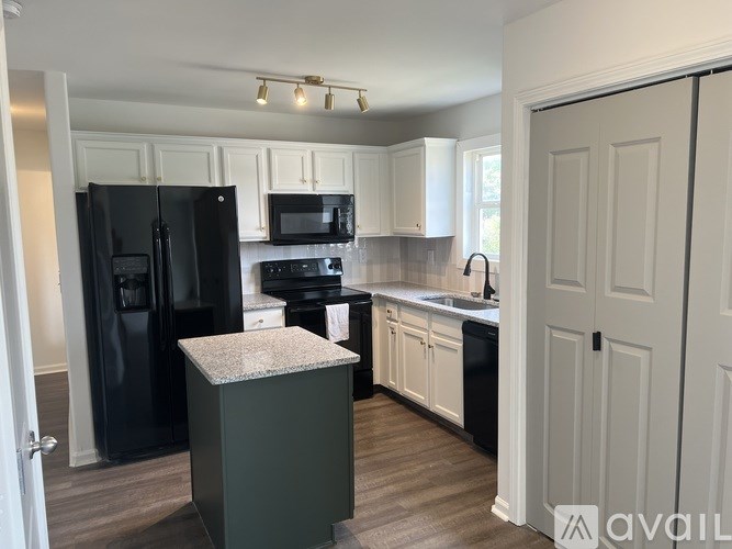 A kitchen with black appliances and white cabinets.