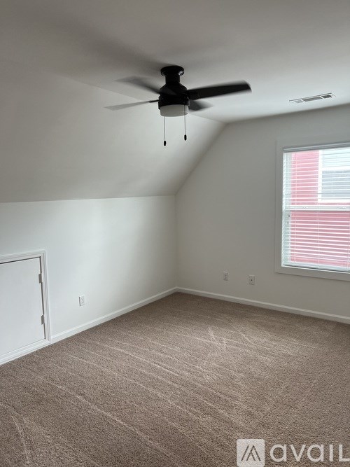 A room with a ceiling fan and carpeted floor.