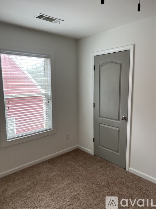 A room with a grey door and a window with red blinds.