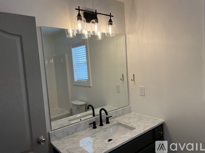 A bathroom with a sink, mirror, and light fixture.