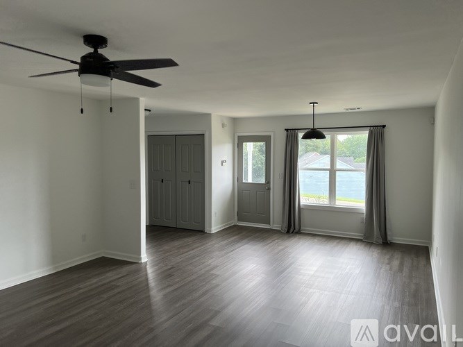 A spacious room with a ceiling fan and a view of the backyard through the window.