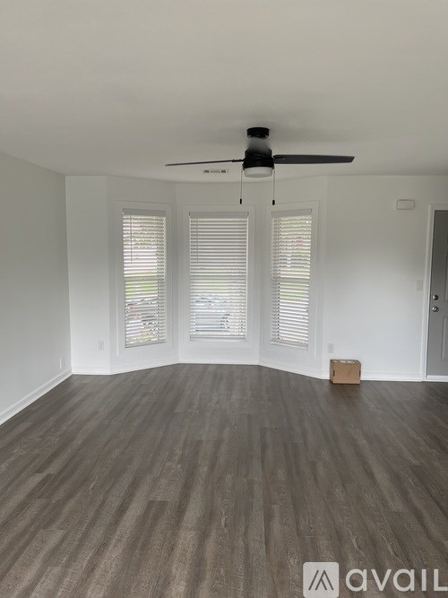 A room with a ceiling fan and wooden flooring.