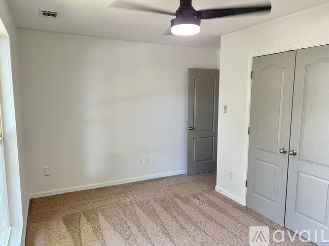A room with a ceiling fan and two doors.