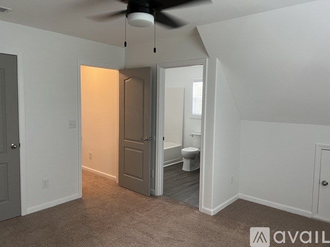 A room with a ceiling fan and a toilet in the corner.