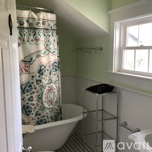 A bathroom with a white tub and a shower curtain with a floral pattern.
