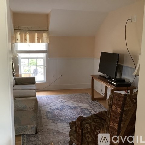 A living room with a television and a window with curtains.