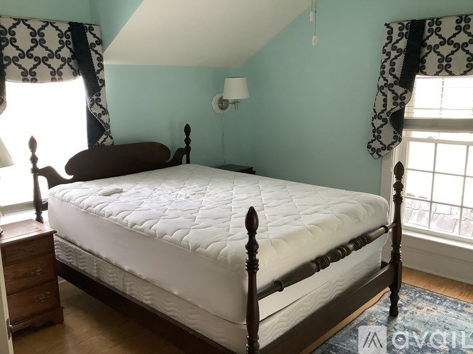 A bed with a white mattress and a wooden frame in a room with blue walls.