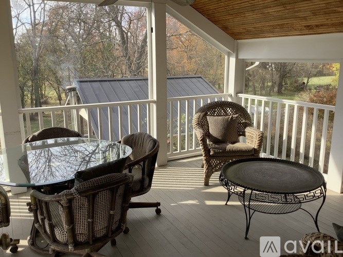 A patio with a glass table and chairs overlooking a forest.