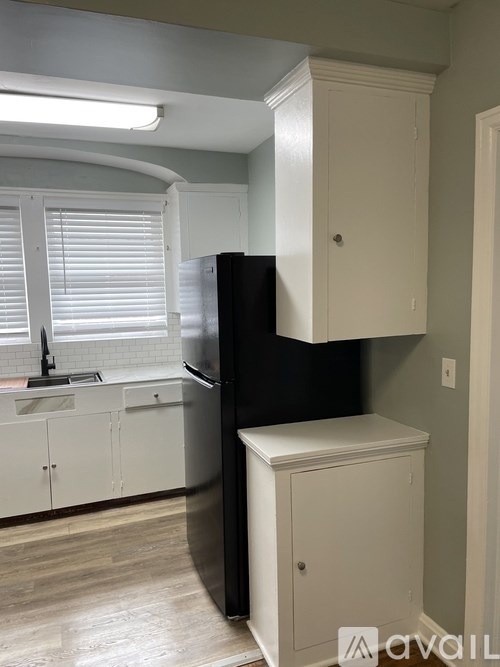 A kitchen with a black refrigerator and white cabinets.